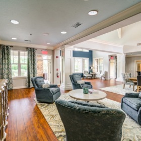 Open resident lounge area with kitchen space, high ceilings, and tables and chairs Open resident lounge area with kitchen space, high ceilings, and tables and chairs