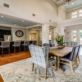 Open resident lounge area with kitchen space, high ceilings, and tables and chairs Open resident lounge area with kitchen space, high ceilings, and tables and chairs