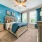 Open, carpeted bedroom with closet and warm lighting overhead and next to the bed
