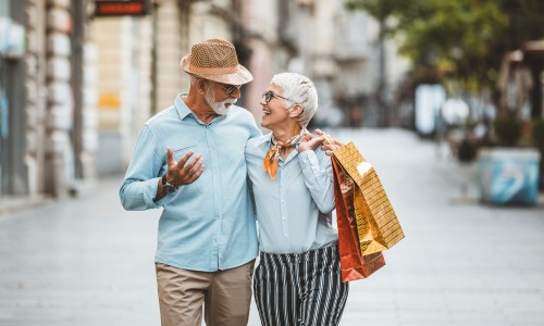 a man and woman holding shopping bags while walking