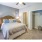 Open, carpeted bedroom with closet and warm lighting overhead and next to the bed