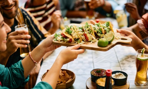 hands holding a tray of tacos